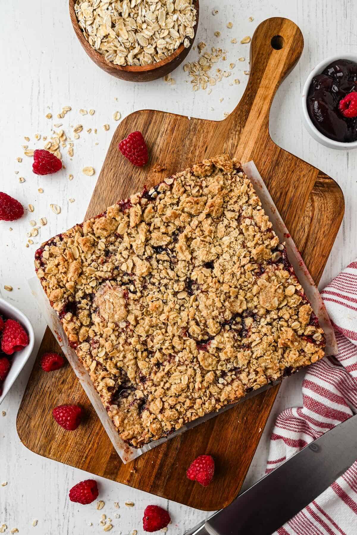 Batch of raspberry oatmeal bars lifted from the baking pan using parchment paper.