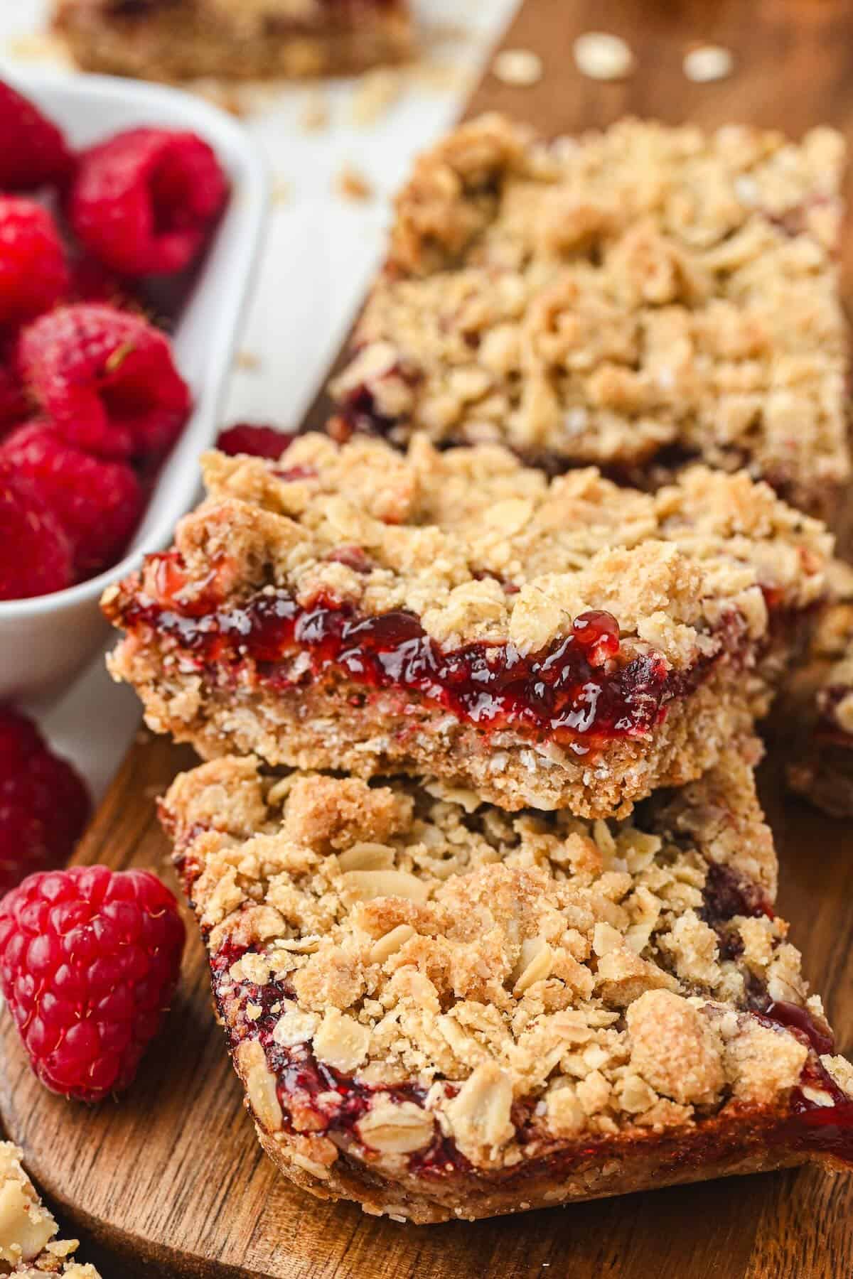 Stacked raspberry oatmeal bars showing layers of buttery oat crumble and raspberry filling.