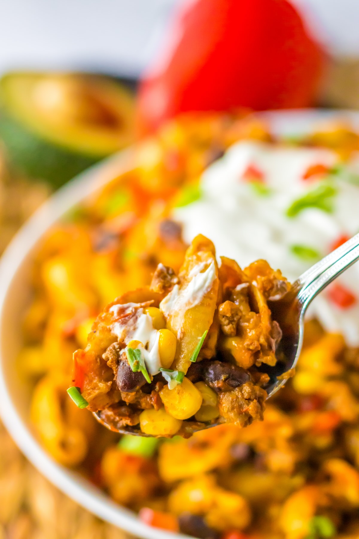 Serving spoon scooping cheesy taco pasta from a slow cooker.