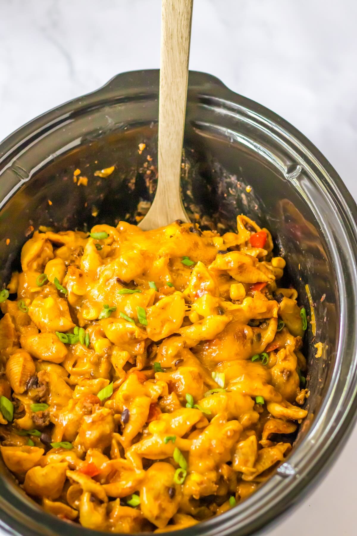 Overhead view of cheesy crockpot taco pasta made with ground beef, black beans, corn, and pasta.
