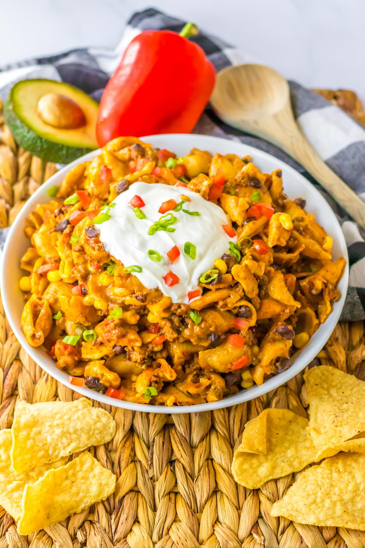 Slow cooker taco pasta topped with sour cream, tomatoes, shredded cheese, and green onions.