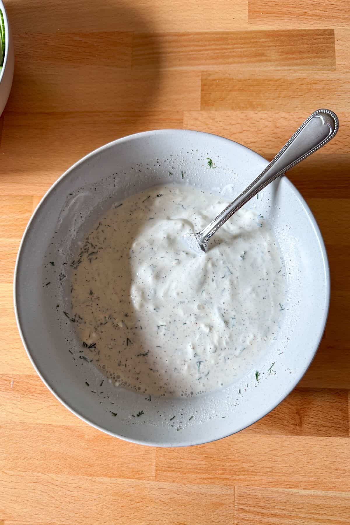 Mixing sour cream dill dressing for cucumber salad.