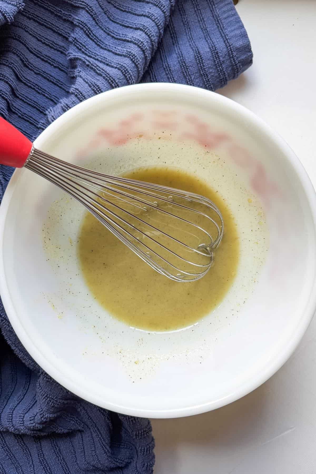 Tangy vinegar and oil dressing for potato salad with bacon and green onions ready for a summer potluck.