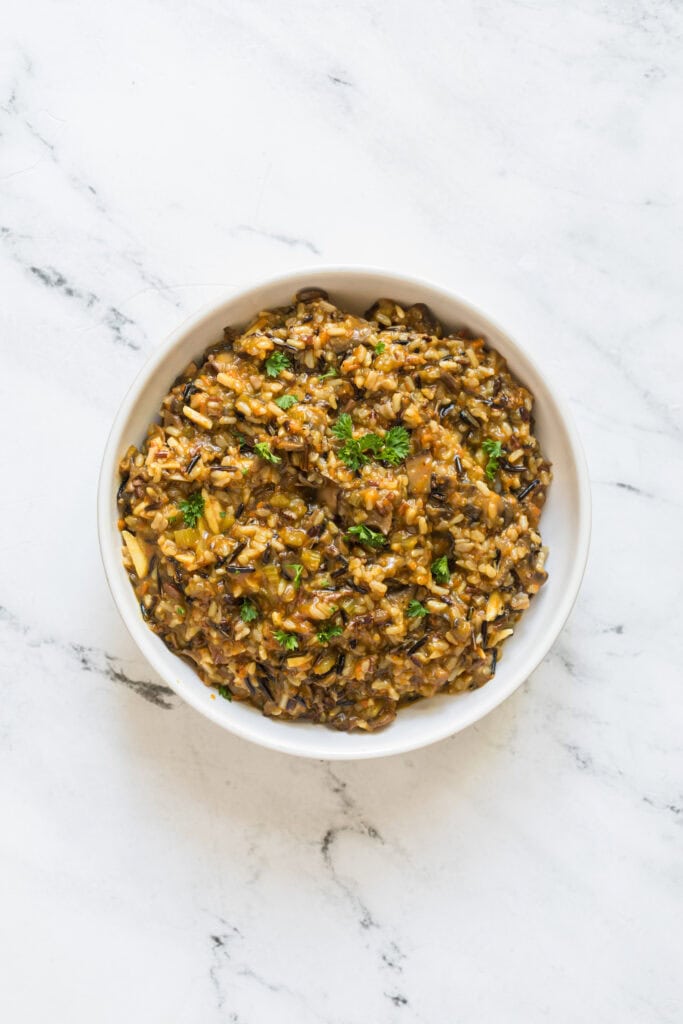 Fresh chopped parsley being stirred into cooked wild rice pilaf.