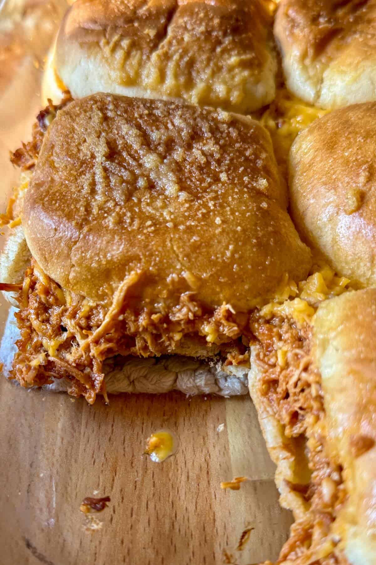 Close-up of a BBQ chicken slider with shredded chicken and melted mozzarella cheese.