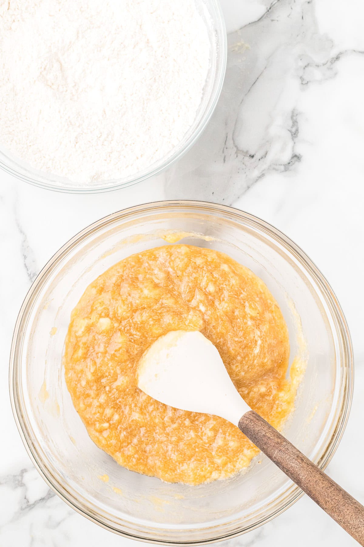 Mashed bananas mixed with melted butter and brown sugar for banana bread batter.