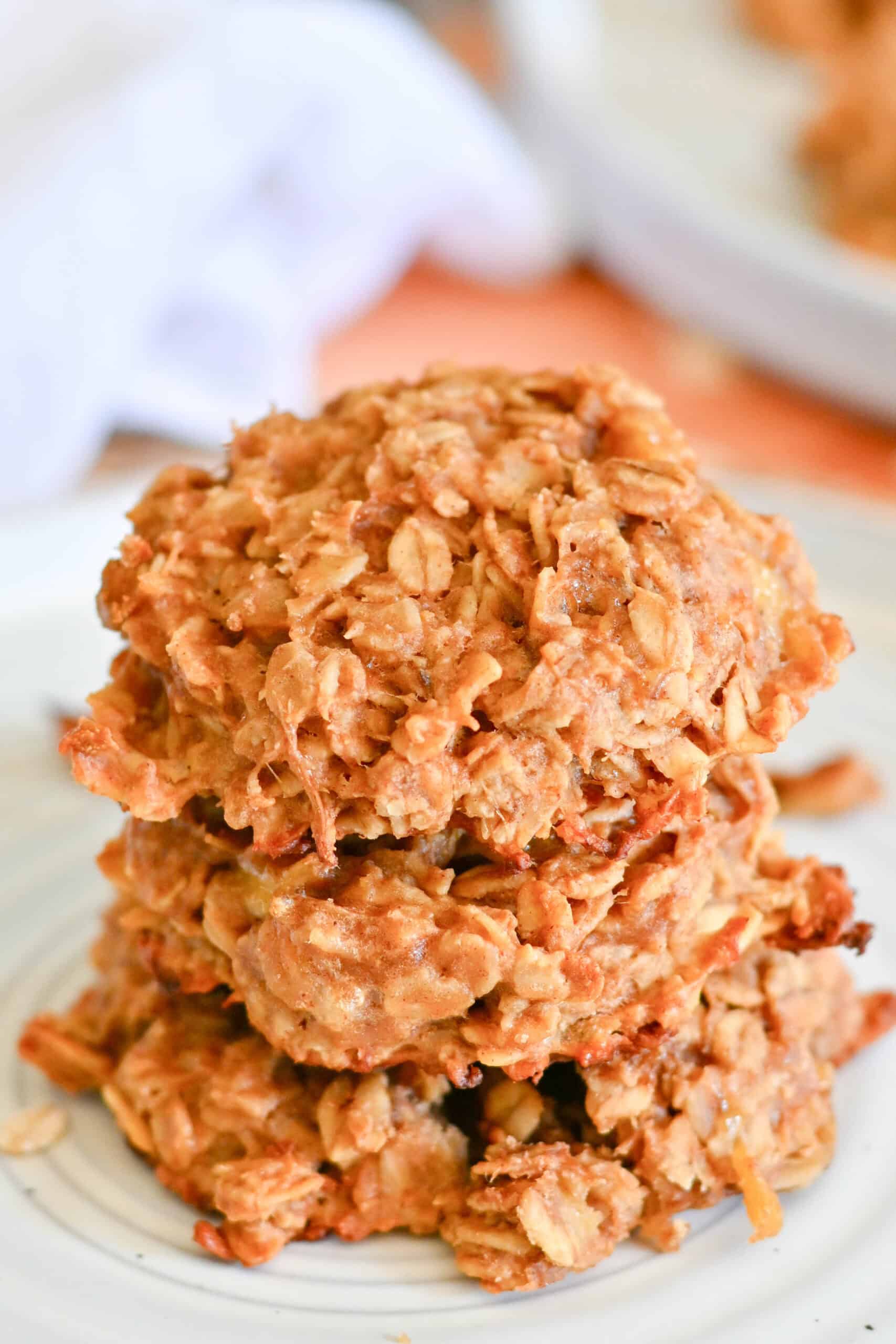 Stack of banana oatmeal breakfast cookies on a white plate with a glass of milk.
