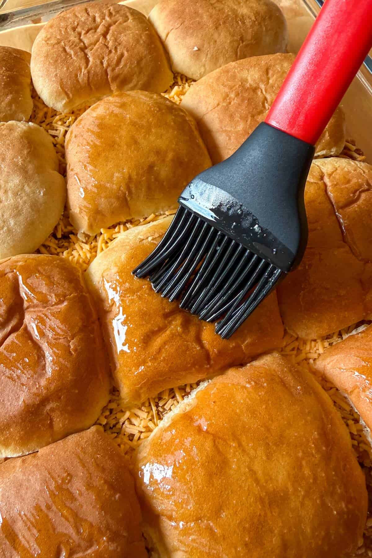 Brushing the tops of Hawaiian rolls with a meltted butter mixture.