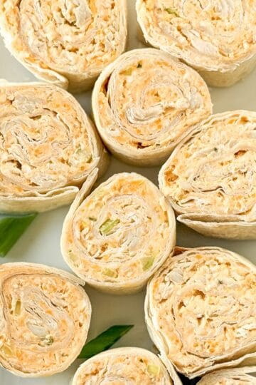 Buffalo chicken pinwheels on a platter as an appetizer.