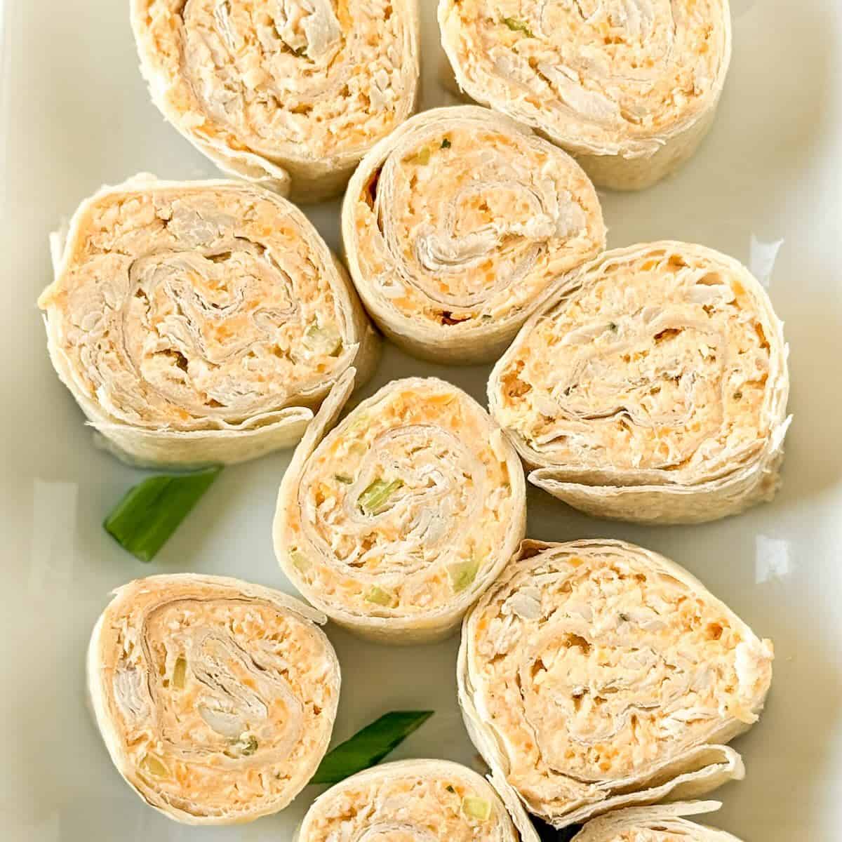 Buffalo chicken pinwheels on a platter as an appetizer.