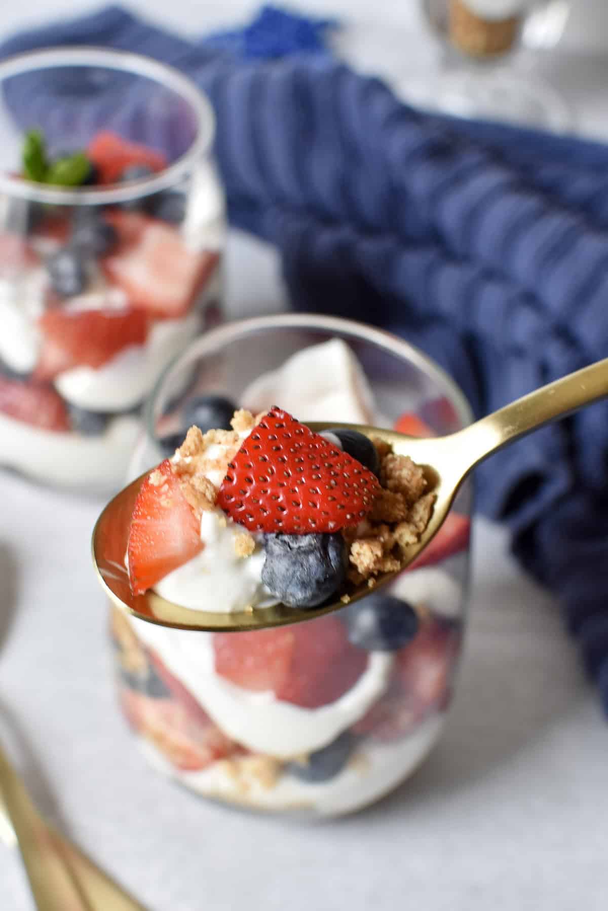 Spoonful of no bake cheesecake parfait with berries and graham cracker crumbs.