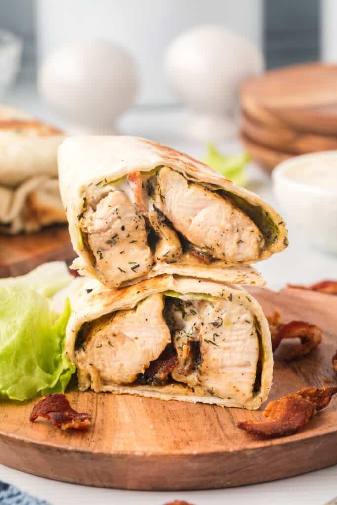 Chicken bacon ranch wrap cut in half showing chicken, bacon, lettuce, and ranch dressing.