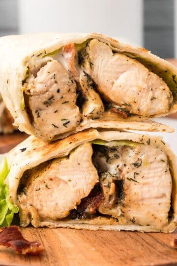 Chicken bacon ranch wrap cut in half showing chicken, bacon, lettuce, and ranch dressing.