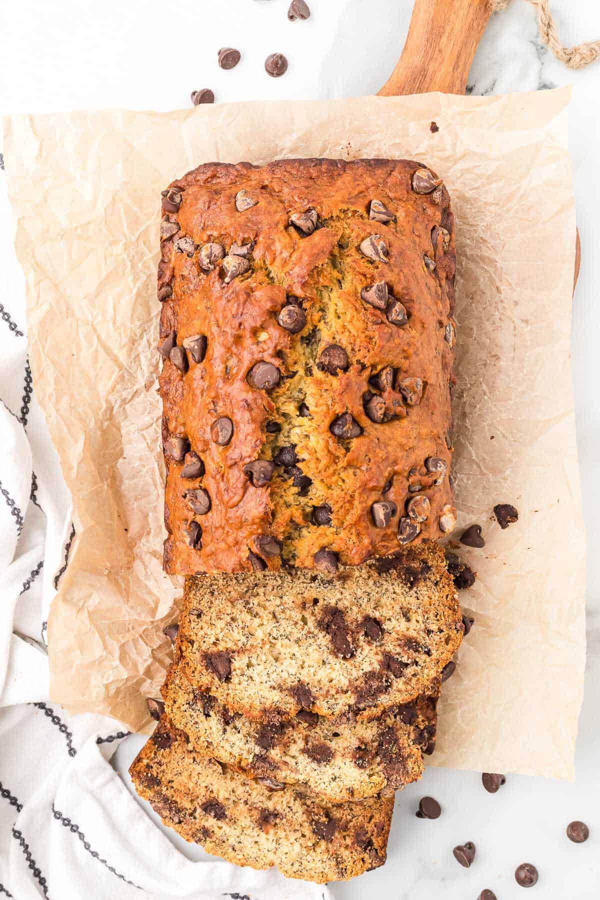 Homemade chocolate chip banana bread sliced and served on parchment paper.