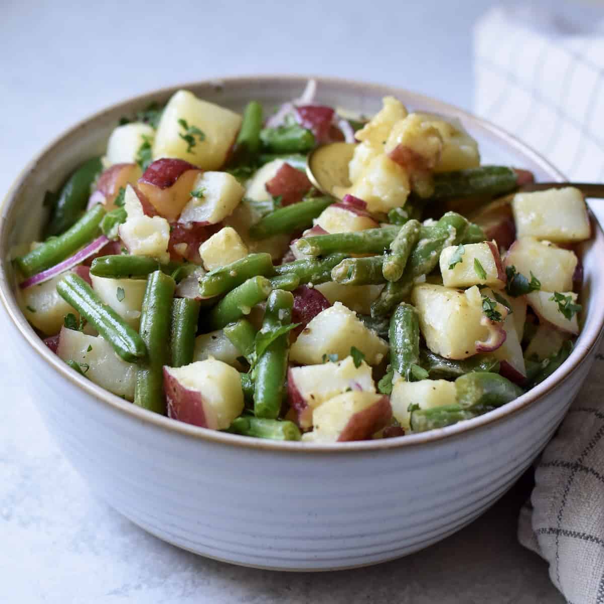 A large bowl of green beans and potato salad, perfect for feeding a crowd.