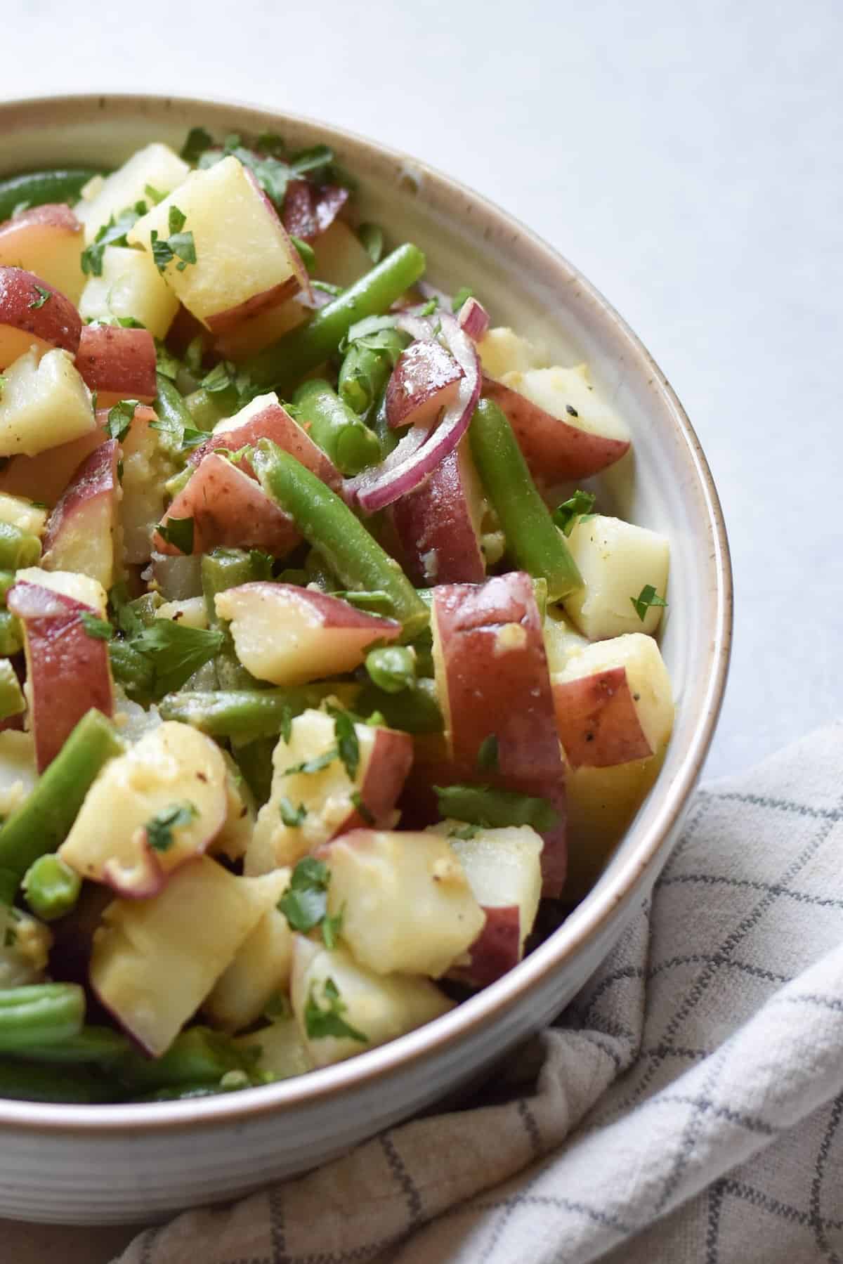 A summertime cookout side dish for fresh green beans and red potatoes, topped with freshly chopped parsley.