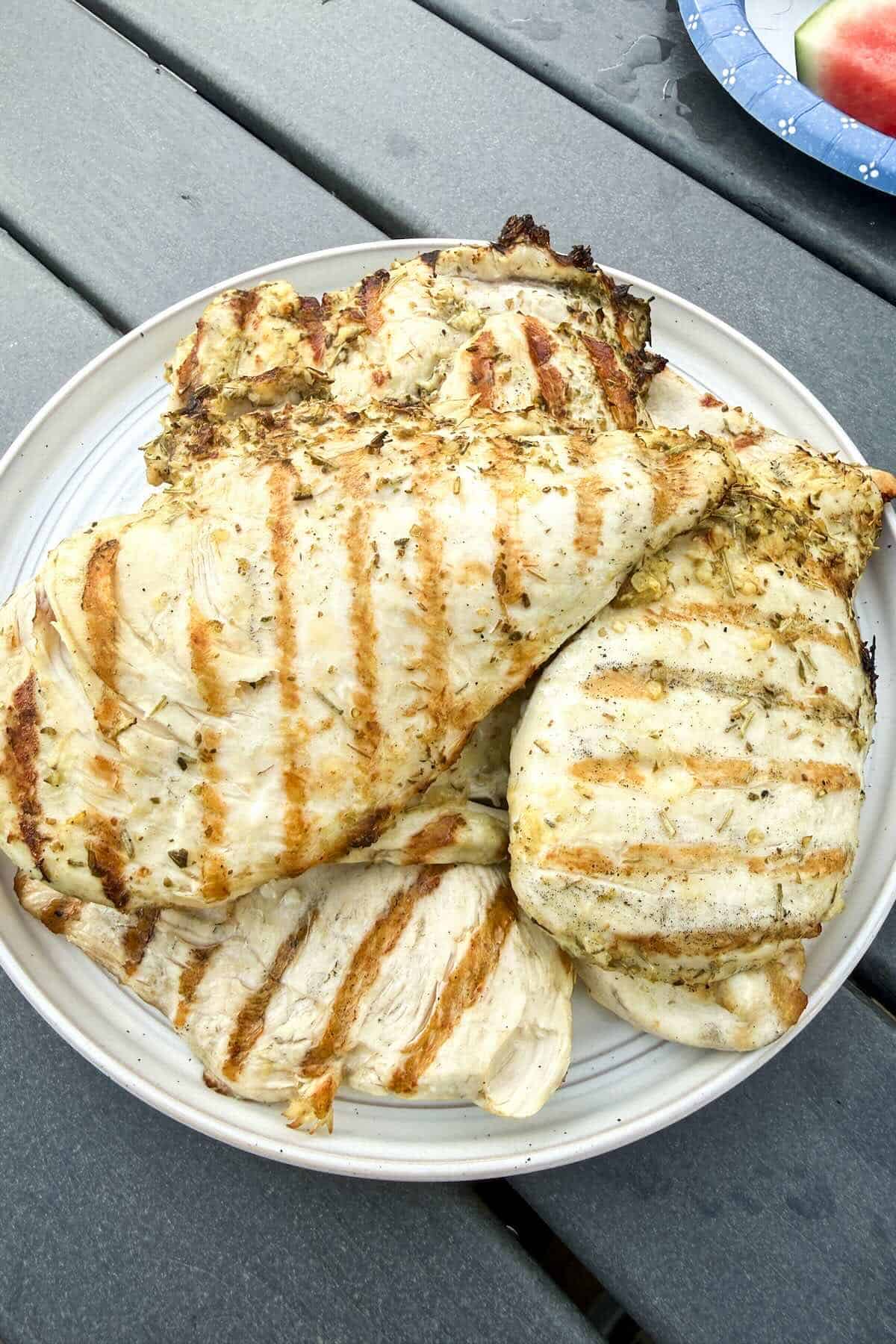 A platter of grilled chicken resting on a picnic table before serving.