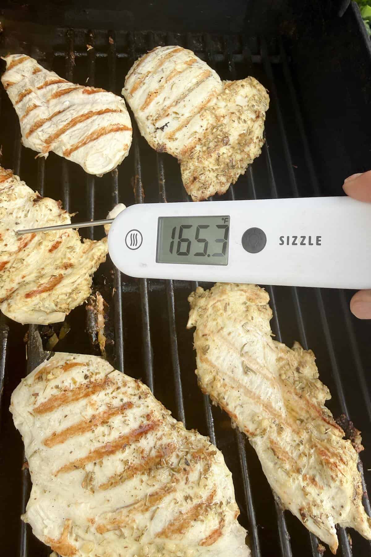 Chicken breasts grilling over medium-high heat after marinating in an herb marinade.