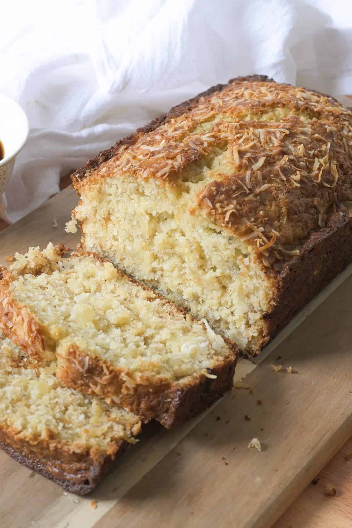 Hawaiian banana bread with pineapple and coconut sliced on a wooden board.