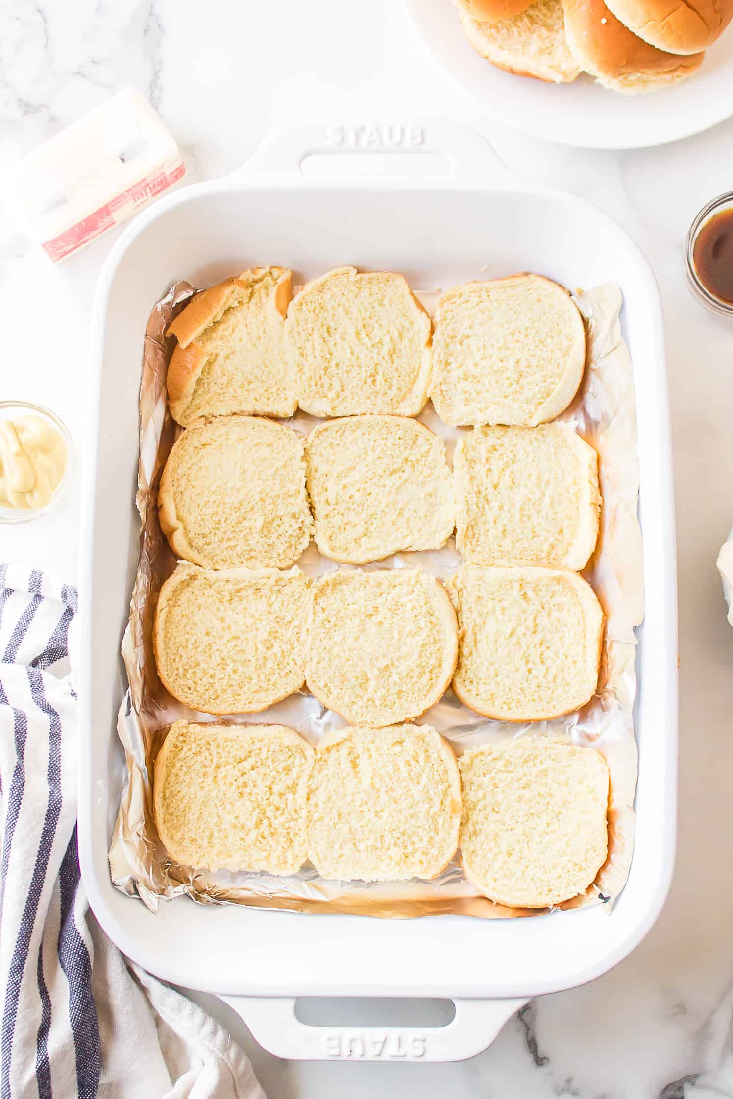 Bottom halves of Hawaiian rolls arranged in a baking pan for roast beef sliders.