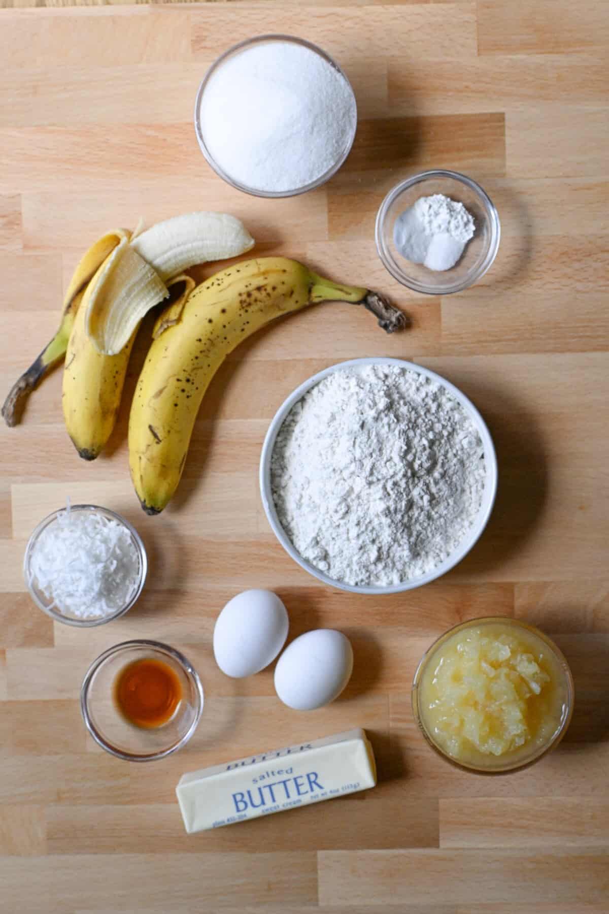 Ingredients for Hawaiian banana bread including banana, pineapple, coconut, flour, sugar, eggs and butter.