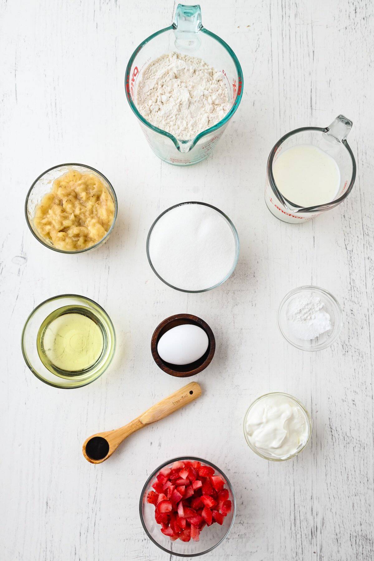 Ingredients needed to make strawberry banana muffins including bananas, strawberries, flour, and sour cream.