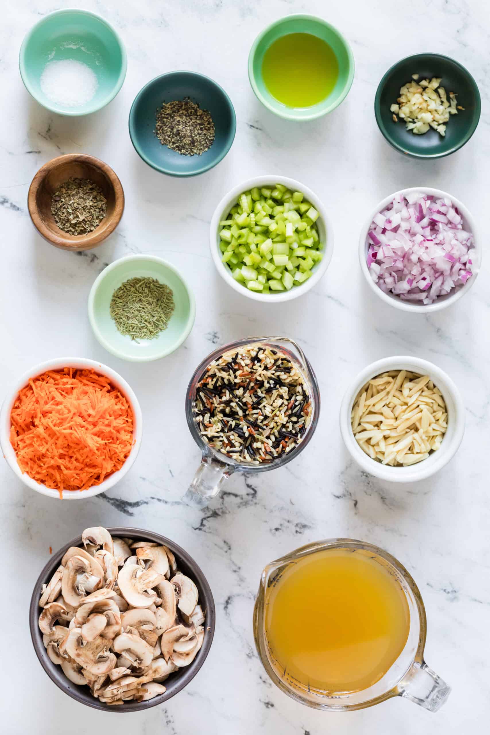 Ingredients for Instant Pot wild rice pilaf including wild rice blend, mushrooms, carrots, celery, onion, garlic, broth, rosemary, parsley, and almonds.