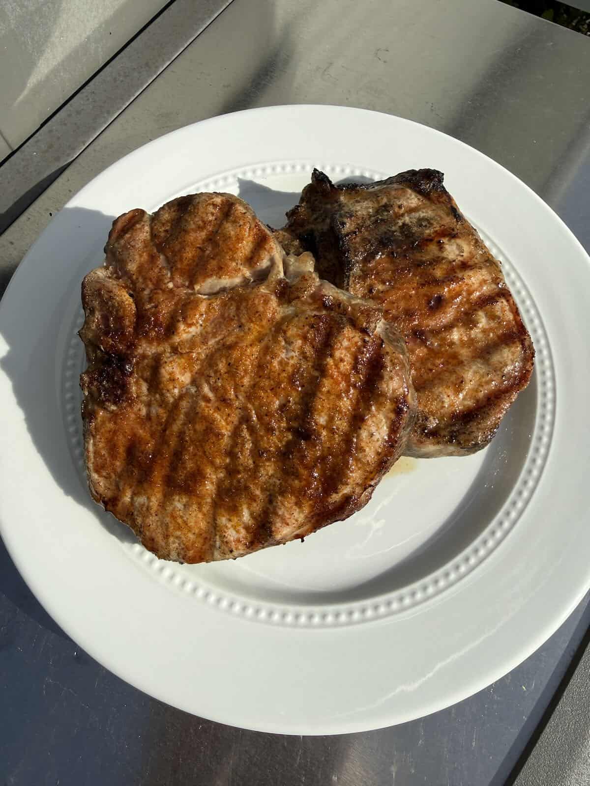 Juicy grilled pork chops with farmhouse BBQ rub served on a platter after grilling.