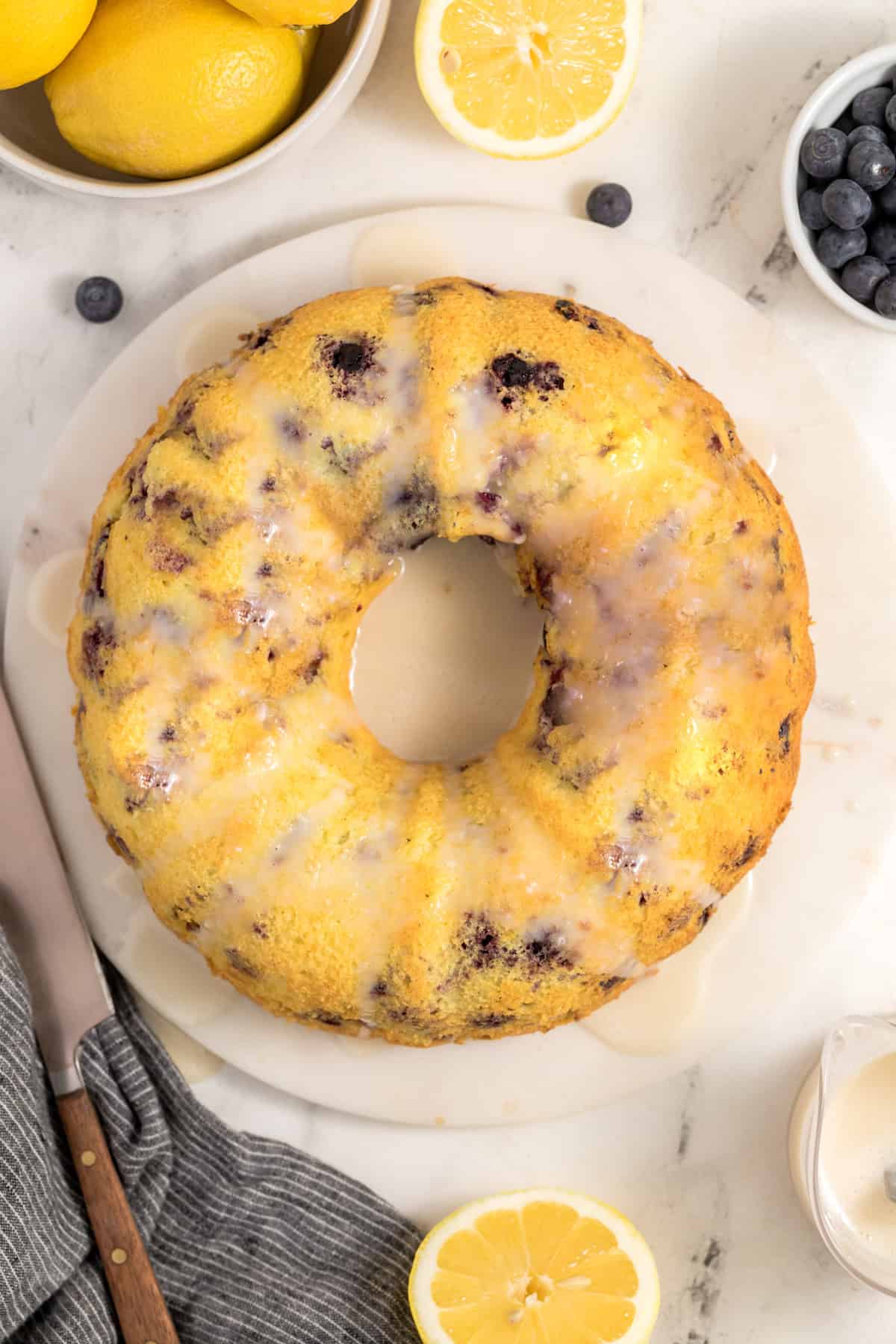 Whole lemon blueberry bundt cake topped with lemon glaze on a cake stand.