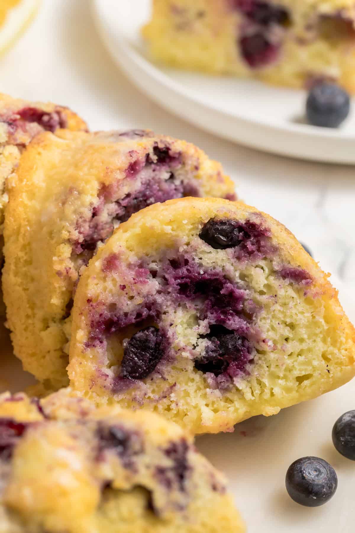 Close-up slice of lemon blueberry bundt cake made with cake mix showing moist crumb and fresh blueberries.