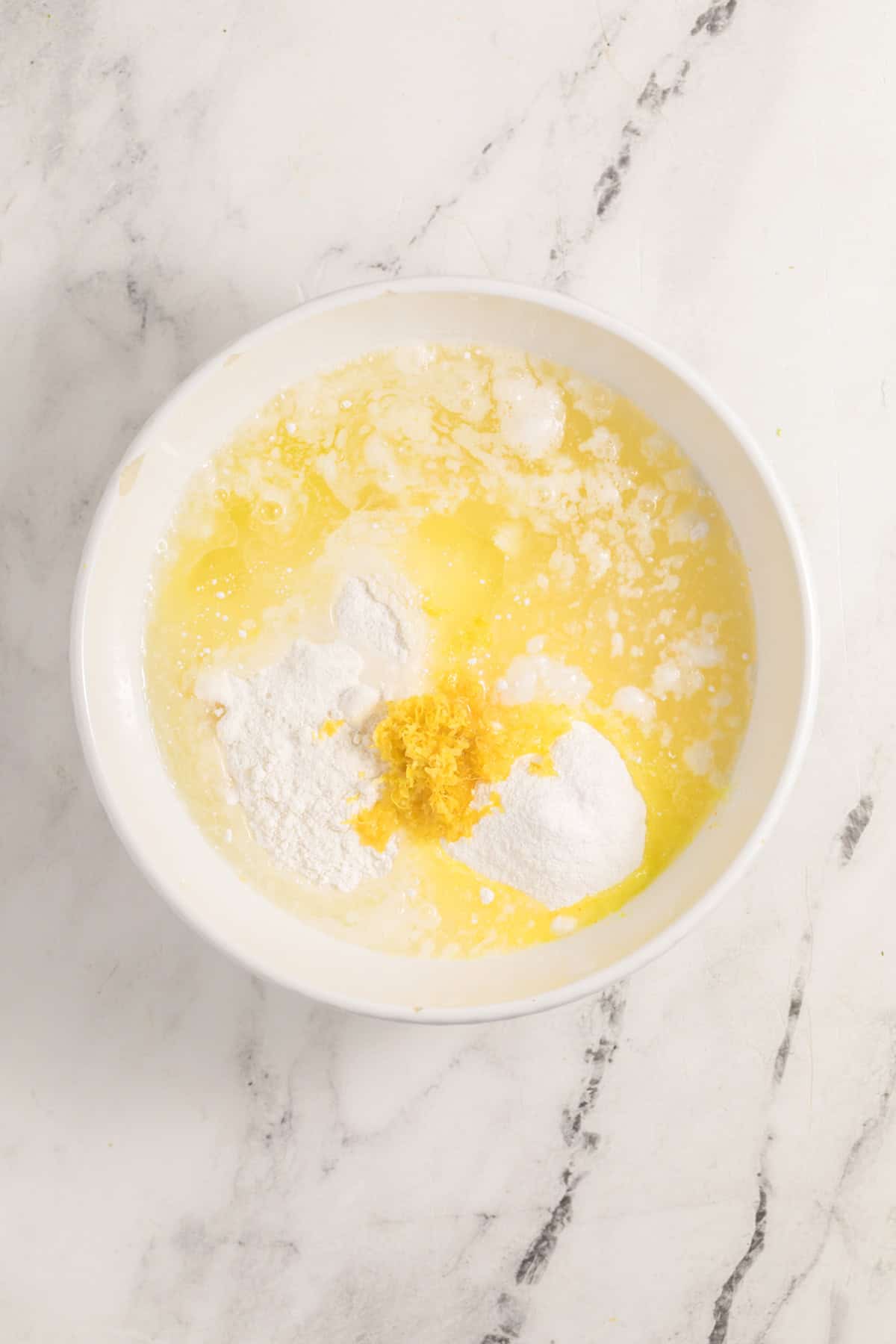 Cake mix, lemon pudding, lemon juice, oil, and egg whites in a mixing bowl.