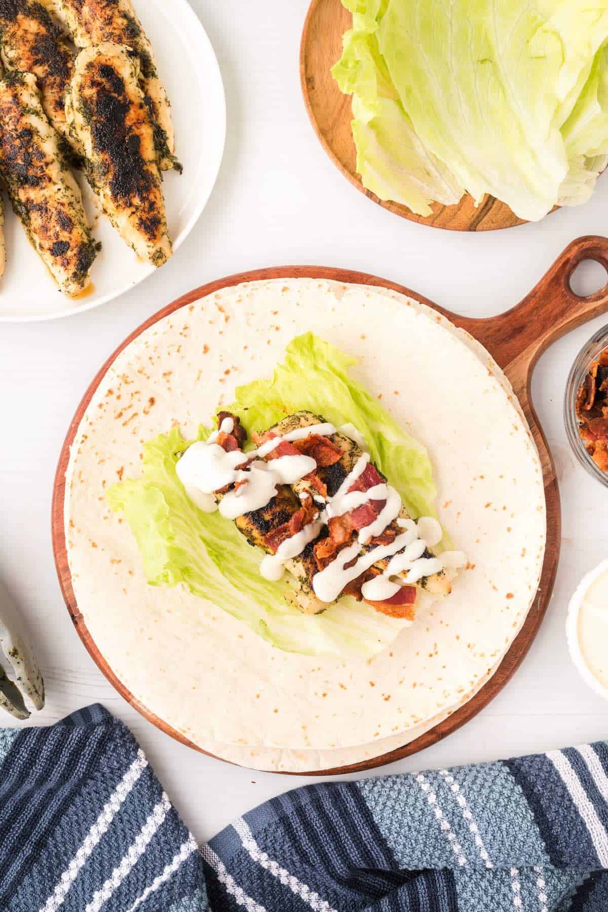 Ranch dressing drizzled over chicken and bacon in a tortilla wrap.