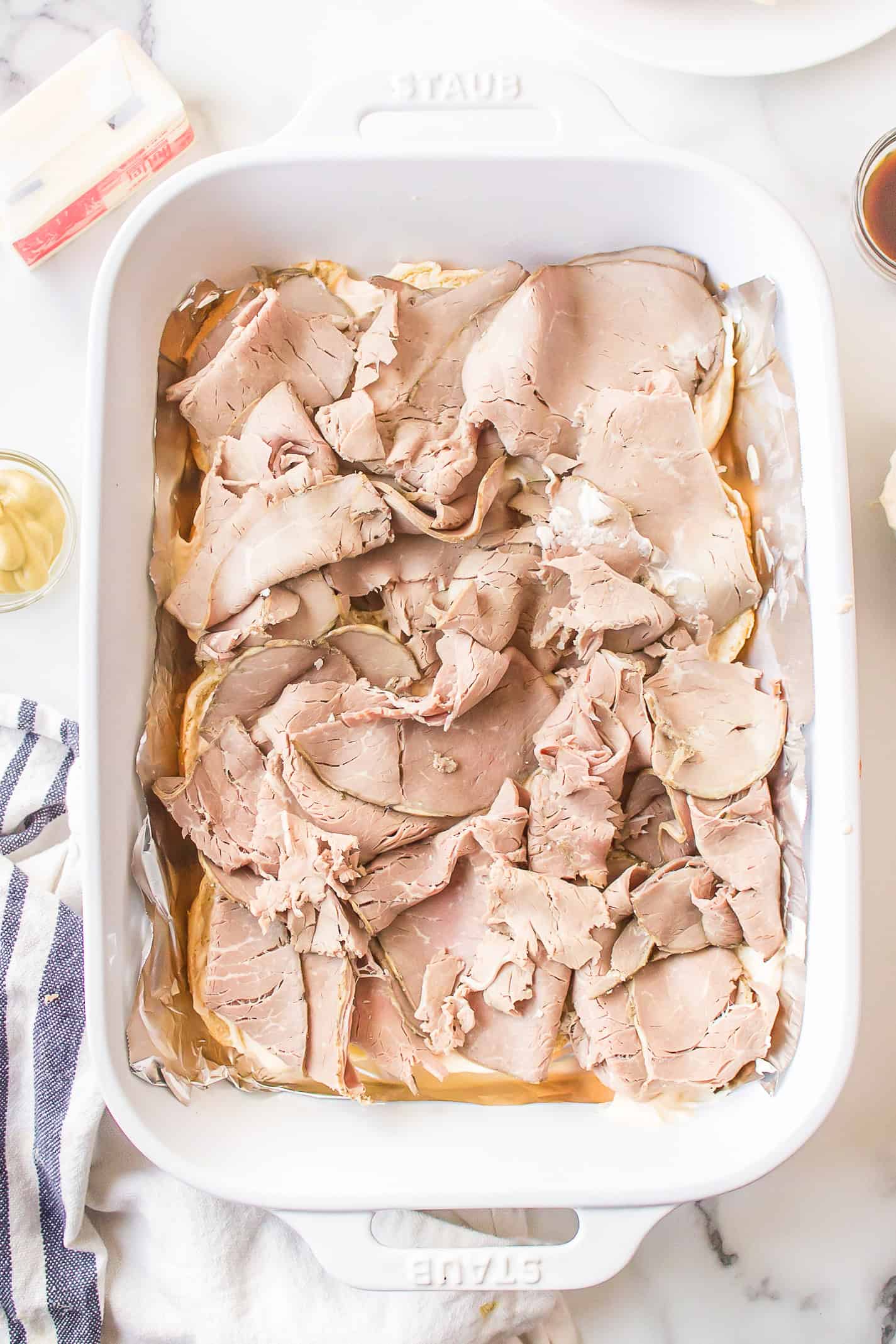 Layers of deli roast beef arranged on Hawaiian rolls before adding cheese.