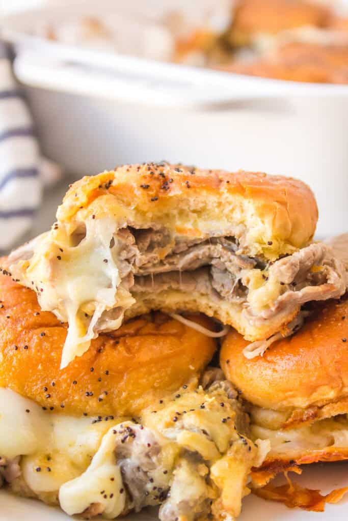 Close-up of a roast beef slider with provolone cheese on a Hawaiian roll.