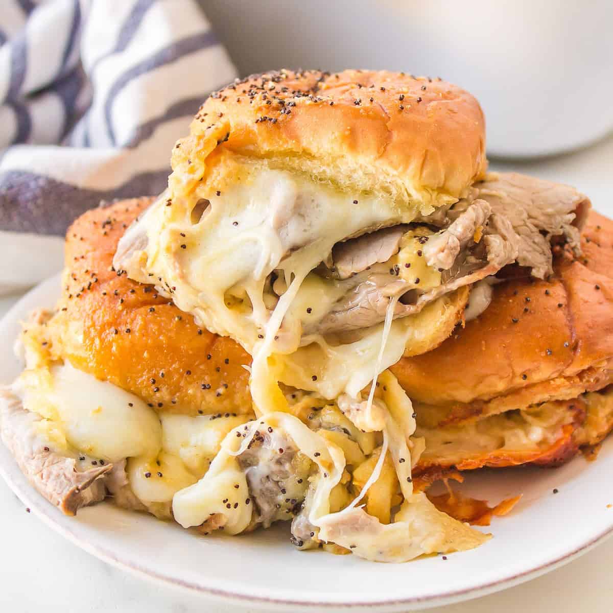 Roast beef sliders on Hawaiian rolls with provolone cheese and horseradish sauce.