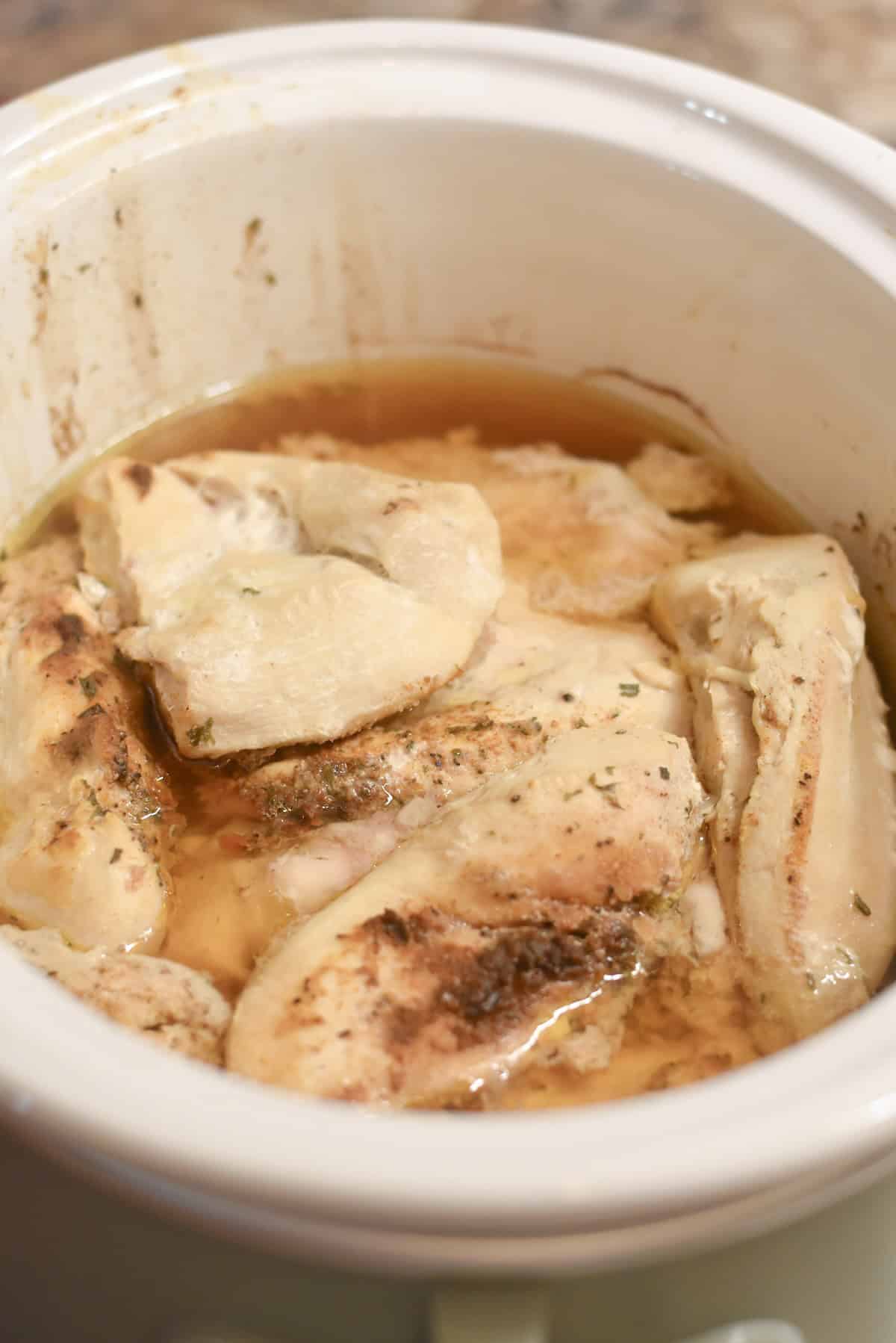 Cooked chicken breasts in slow cooker ready to be shredded.