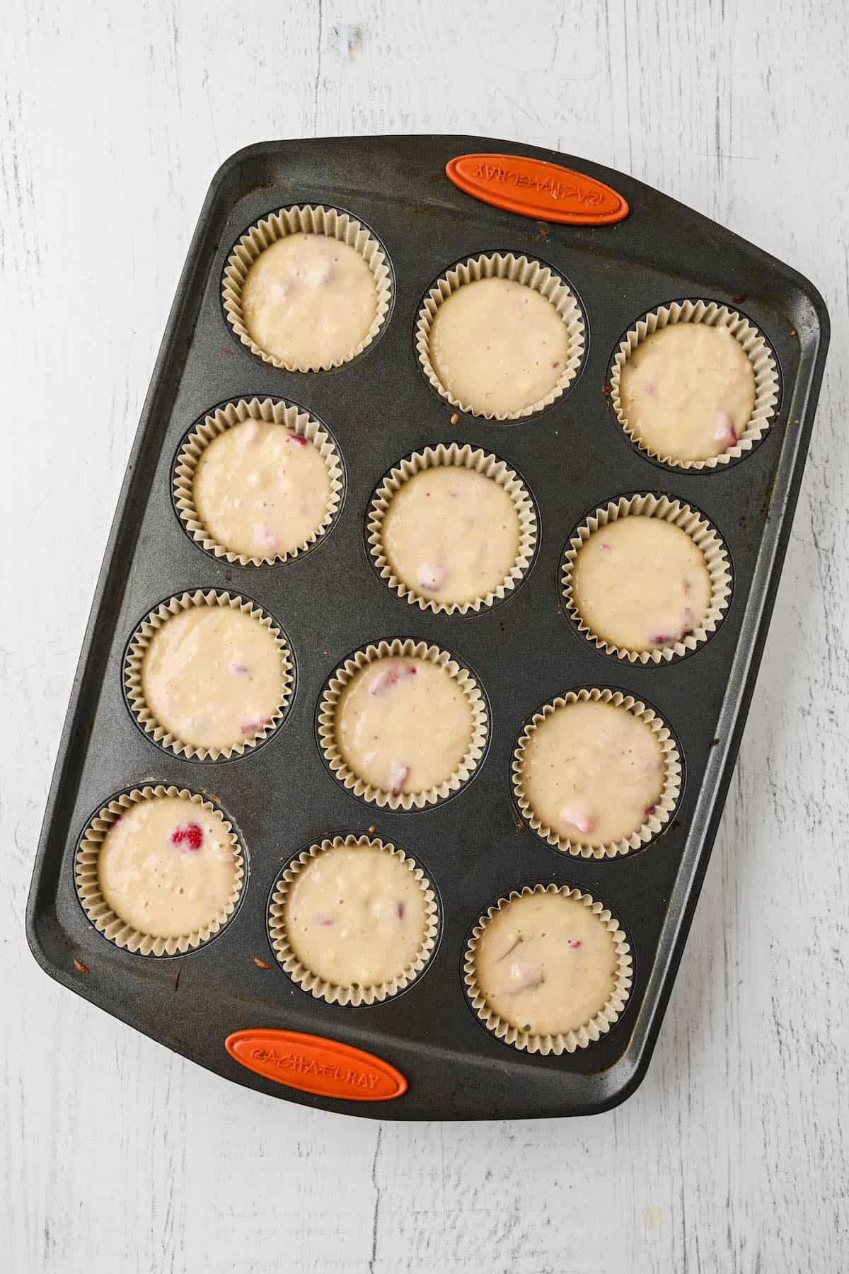 Strawberry banana muffin batter portioned into a lined muffin tin.