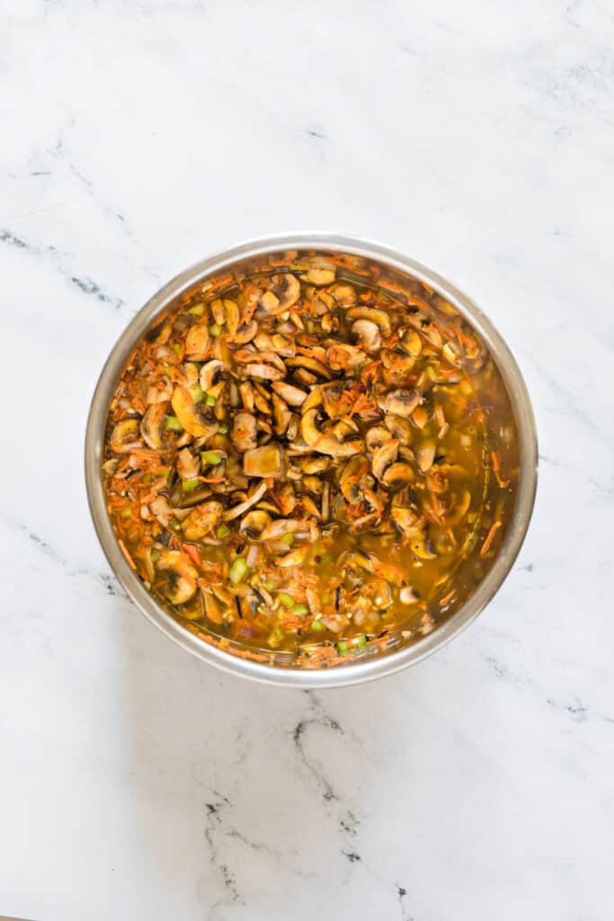 Chicken broth poured over wild rice and vegetables before pressure cooking.