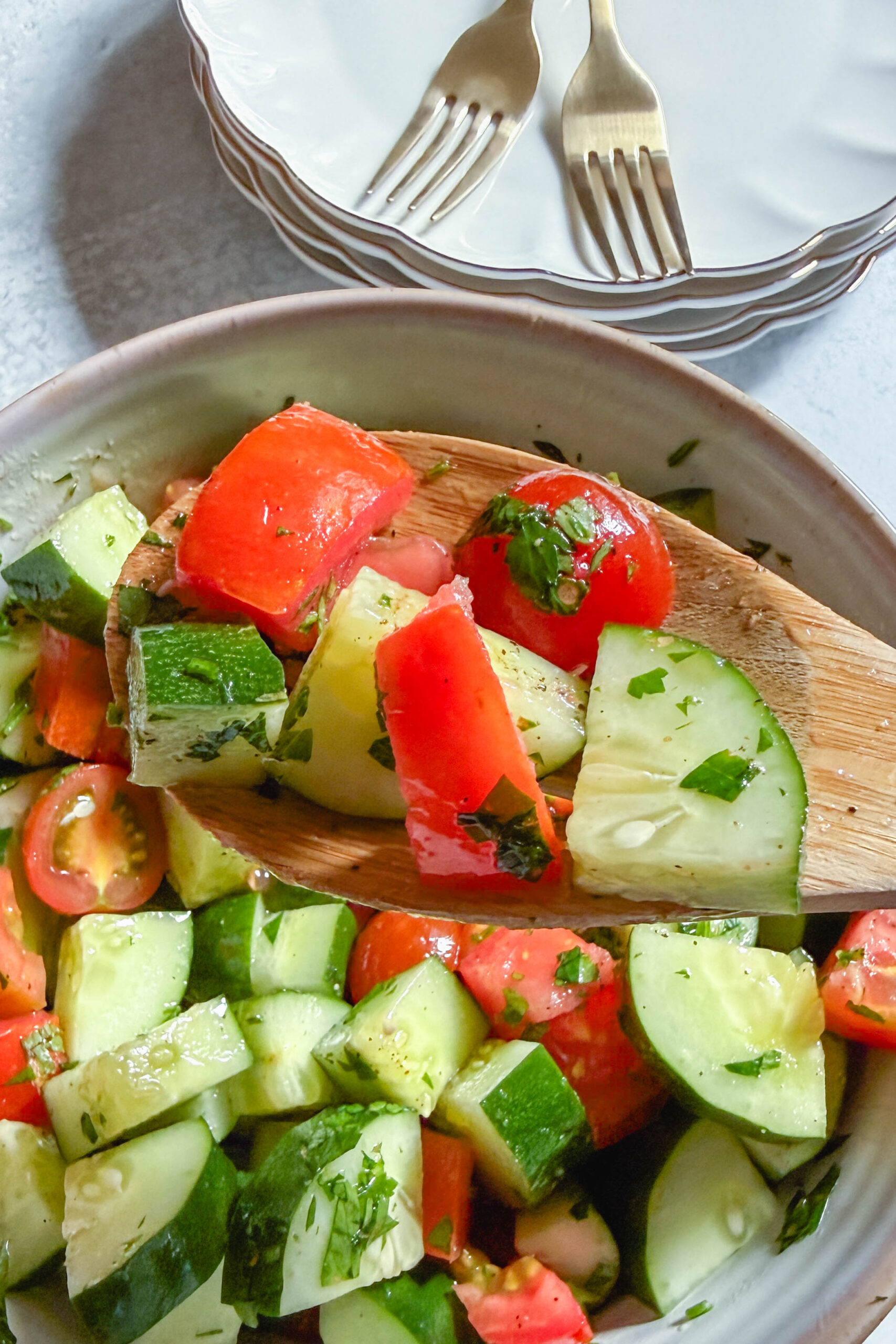 Close-up of cucumber tomato salad with fresh parsley and lemon dressing on a fork.