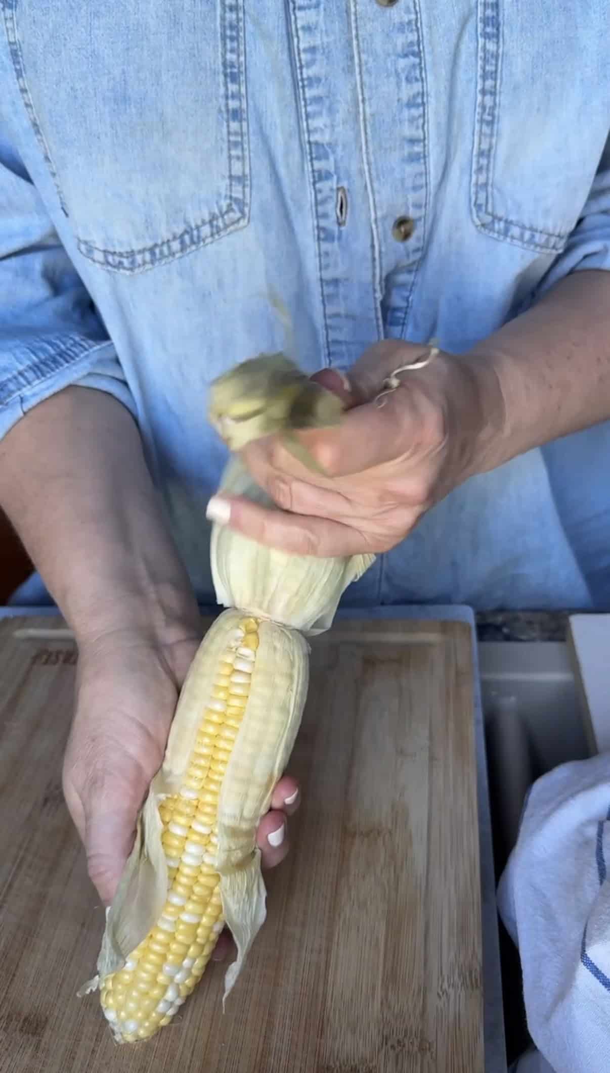 Shucking sweet corn at the kitchen counter.