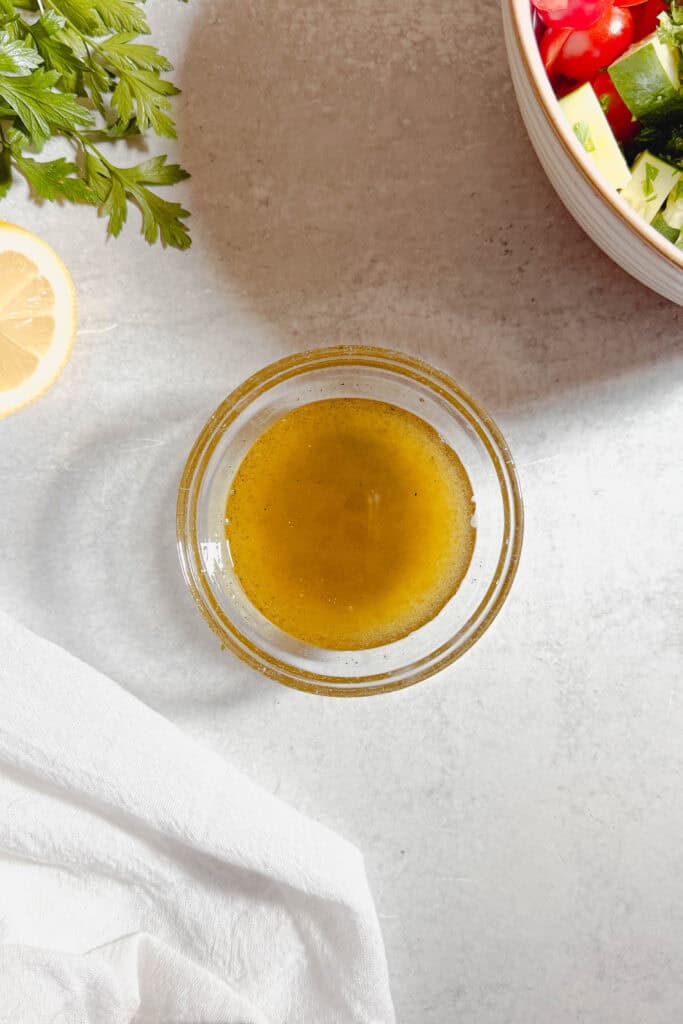 Whisked olive oil, lemon juice and salt for cucumber tomato salad dressing.