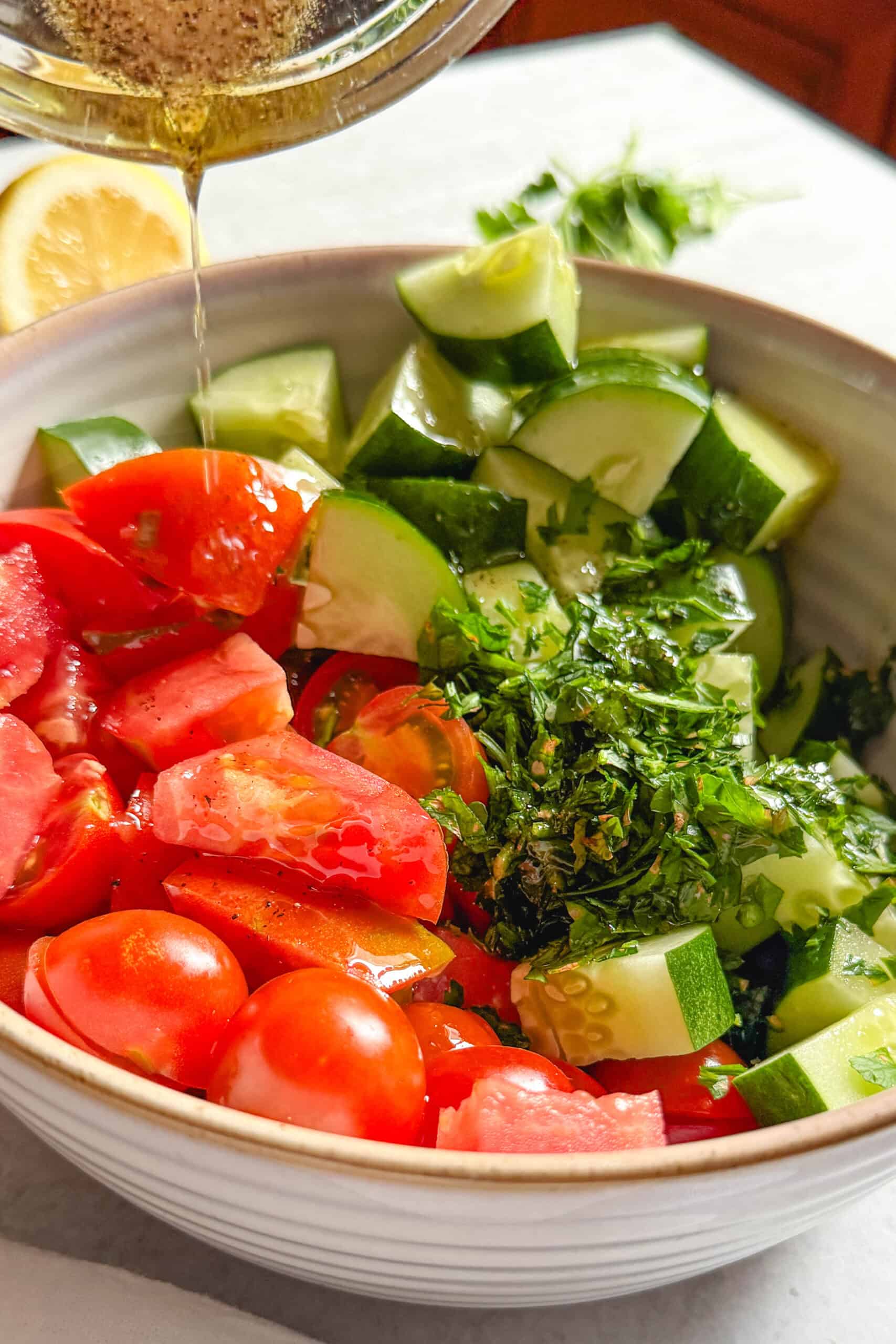Adding a simple lemon juice and olive oil dressing to cucumber tomato salad.