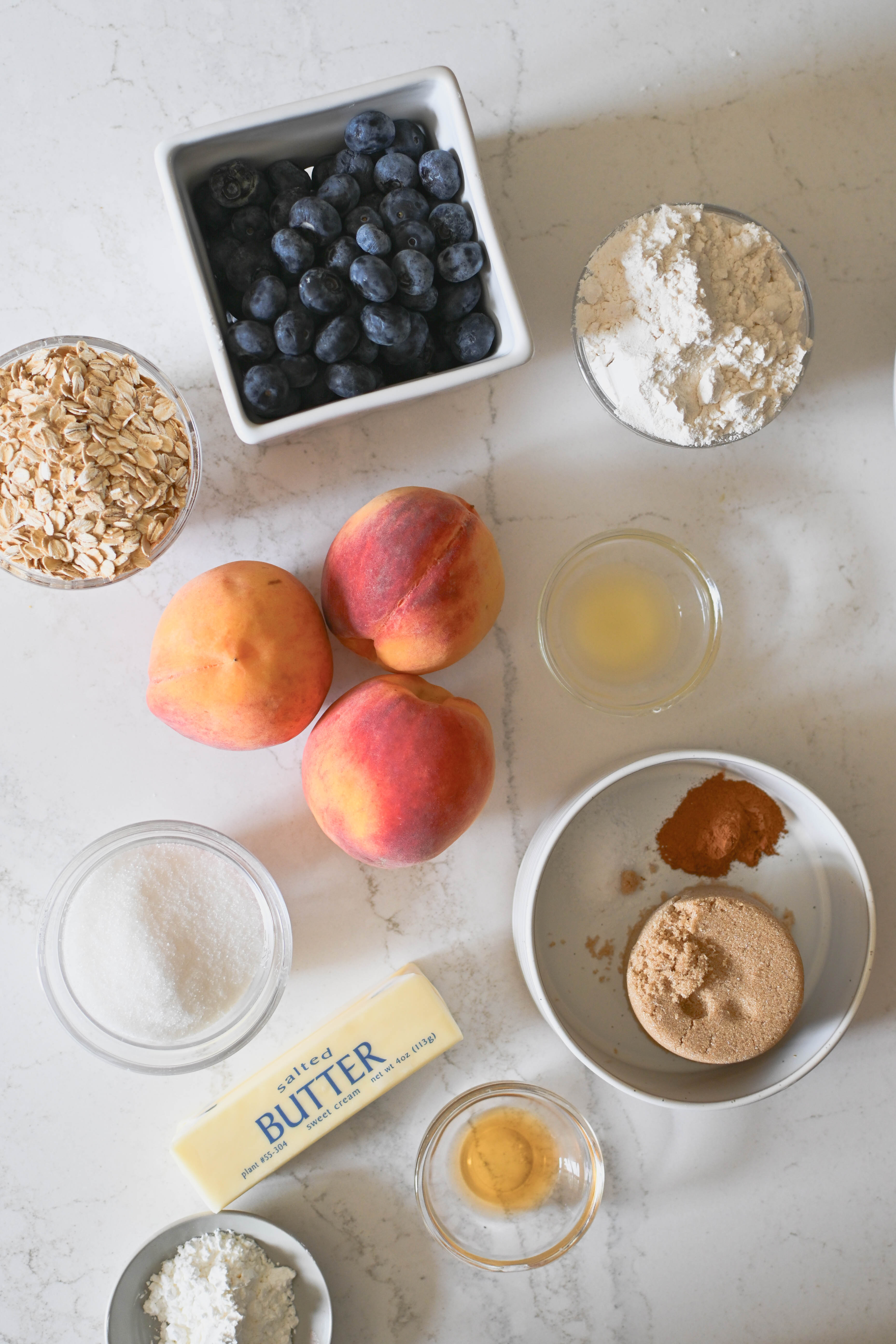 Ingredients to make a cobbler with peaches, blueberries and a buttery oatmeal brown sugar topping.