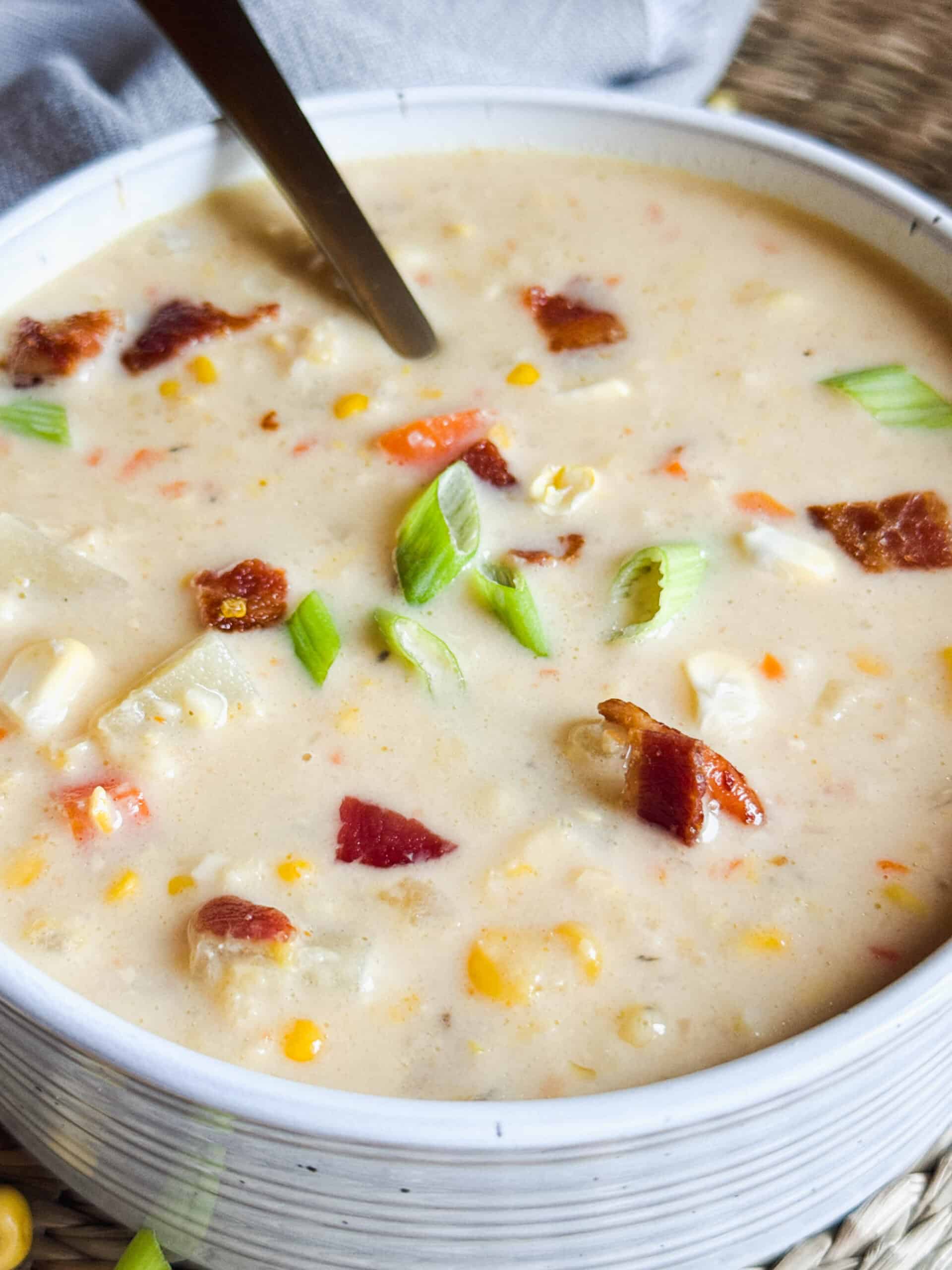 A corn chowder from the slow cooker, showing creamy corn, crispy bacon and chopped green onions.