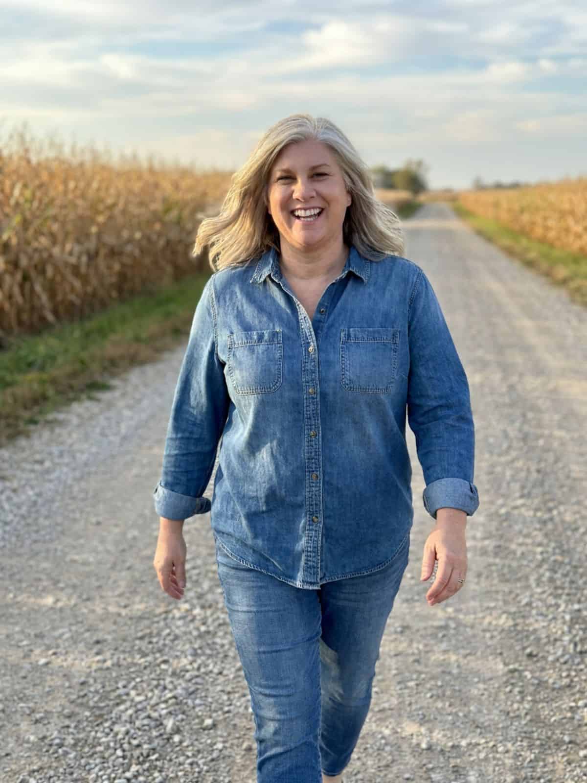 Deanne Frieders walking down an Illinois country road surrounded by cornfields.