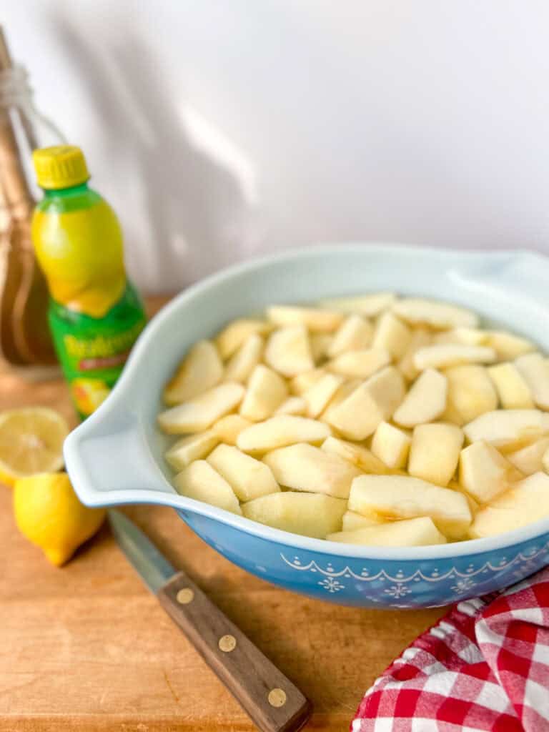 A large bowl filled with water and lemon juice with apple slices to avoid browning.