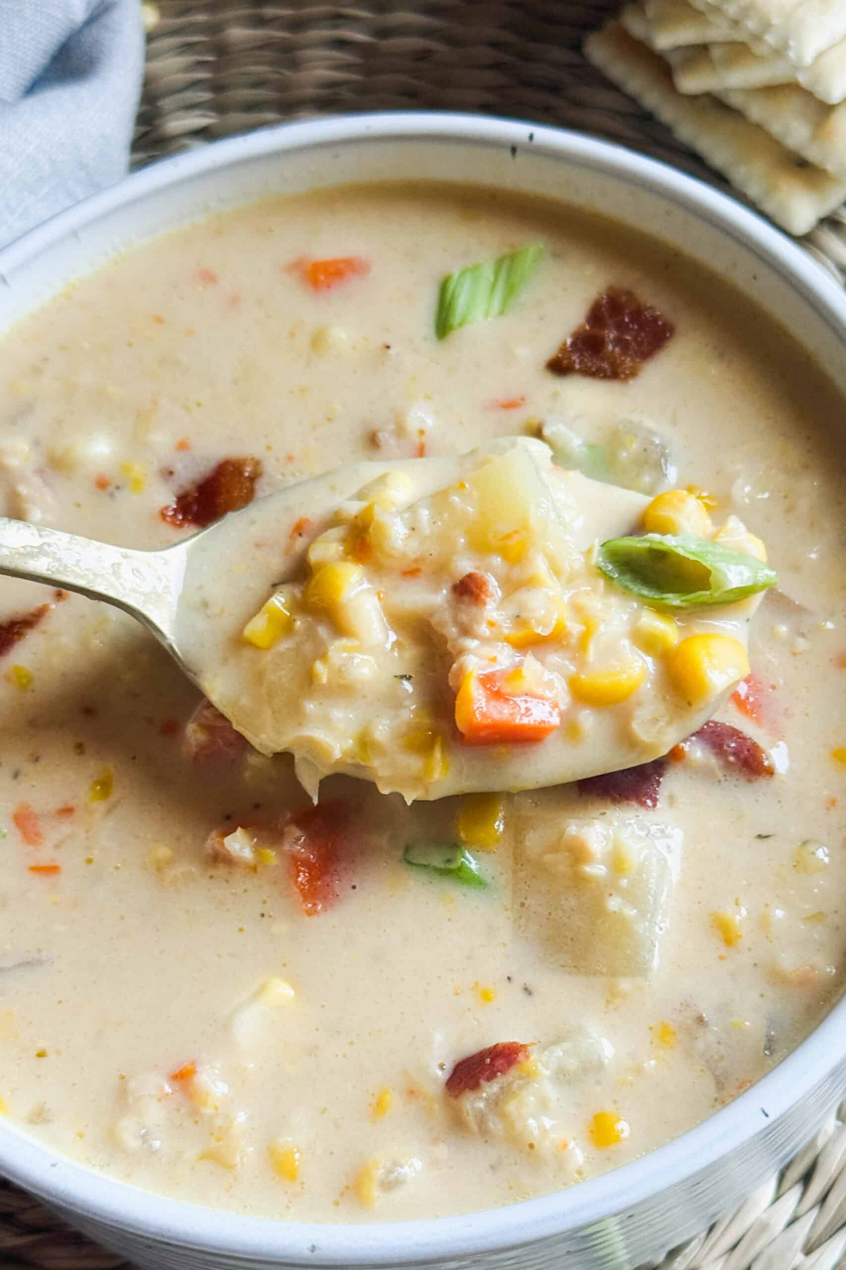 A spoonful of corn chowder with potatoes and carrots.