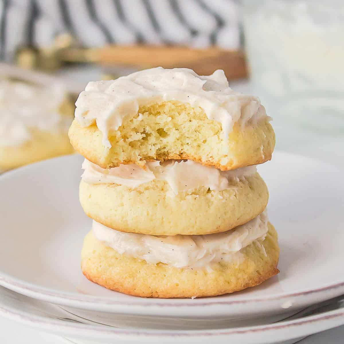 A stack of soft sour cream cookies with buttercream frosting.